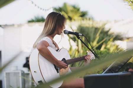 Une jeune chanteuse-guitariste Linkaband chante et joue de son instrument lors d'un concert privé.